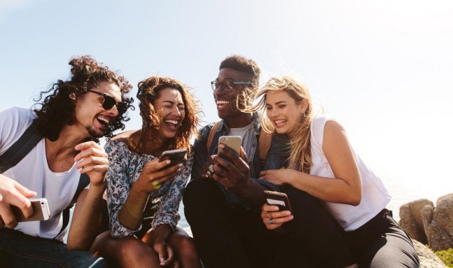 A beautiful community at the heart of all your passions a group of friends sit outside laughing over their cell phones